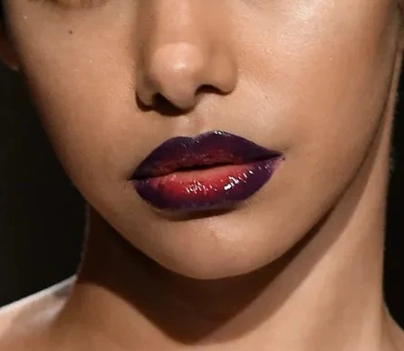 Lips wearing the Smashed Plum lip combo: a deep plum liner melting into a glossy berry center