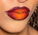 Lips wearing the Sunset lip combo: a burgundy liner fading into a warm, glowing orange center